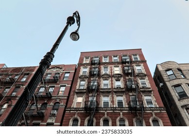 typical lower east side apartment building (tenement with fire escape, windows, lamp post) detail (red brick) - Powered by Shutterstock