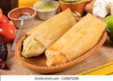 Typical Mexican food dishes with sauces on colorful table. Red and green mole tamales