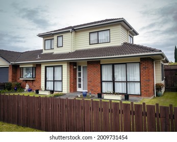 Typical New Zealand suburban house with concrete tile roof and wooden fence. Auckland, New Zealand - July 7, 2021