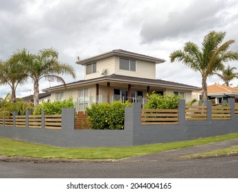 Typical New Zealand suburban house with palm trees, concrete tile roof and concrete fence. Auckland, New Zealand - September 19, 2021