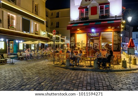 Typical night view of cozy street with tables of cafe in quarter Montmartre in Paris, France. Architecture and landmarks of Paris. Postcard of Paris