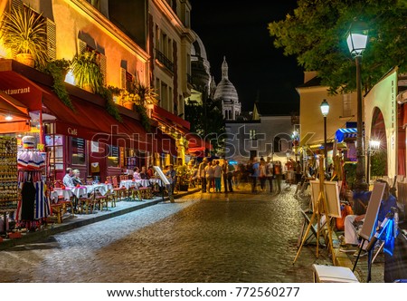 Typical night view of cozy street with tables of cafe and easels of street painters in quarter Montmartre in Paris, France. Architecture and landmarks of Paris. Postcard of Paris