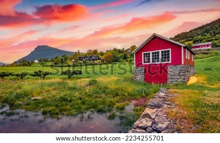 Typical Norwegian countryside with red painted wooden house. Picturesque summer sunrise in Norway, Europe. Traveling concept background.
