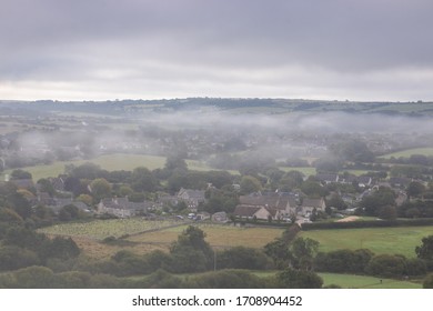 A typical old English village in a valley with mist creeping in over the hills - Shutterstock ID 1708904452
