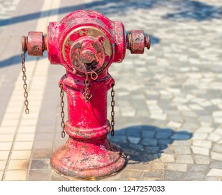 Typical old red fire hydrant with rusty chains on the sidewalk in Hong Kong city on a sunny day