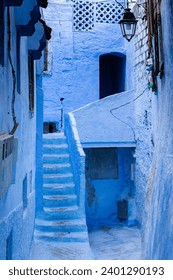 Typical old street with blue painted walls, stairs and doors in the medina of Chefchaouen, Morocco