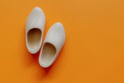 Typical One Single Pair Of Handmade Wooden Shoes On Orange Background With Free Copy Space, Orange Fever Is A Phenomenon In The Netherlands That Occurs During Major Events In Dutch Culture.