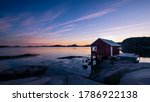 A typical red boat house with a colorful sky with reflections in the ocean on the Swedish west coast, Bohuslän