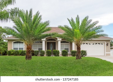 Typical Southwest Florida concrete block and stucco home in the countryside with palm trees, tropical plants and flowers and a bahia grass lawn.