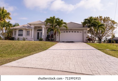 Typical Southwest Florida concrete block and stucco home in the countryside with palm trees, tropical plants and flowers, grass lawn and pine trees. Florida. South Florida single family house