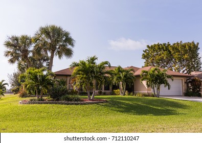 Typical Southwest Florida Concrete Block And Stucco Home In The Countryside With Palm Trees, Tropical Plants And Flowers, Grass Lawn And Pine Trees. Florida. South Florida Single Family House