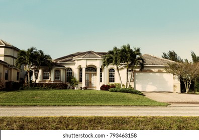 Typical Southwest Florida concrete block and stucco home in the countryside with palm trees, tropical plants and flowers, grass lawn and pine trees. Florida.