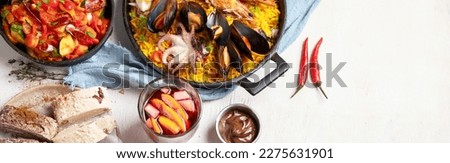 Typical spanish tapas concept. Concept include jamon, chorizo sausage, brushettas,  olives, shrimp, pan with paella, cheese, sangria, churros on a white background. Top view. Panorama with copy space.