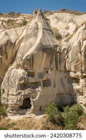 Typical stone dwelling carved in the fairy chimneys with dovecotes carved in the volcanic rock, rock hoodoo in Goreme, Cappadocia, Turkey, vertical