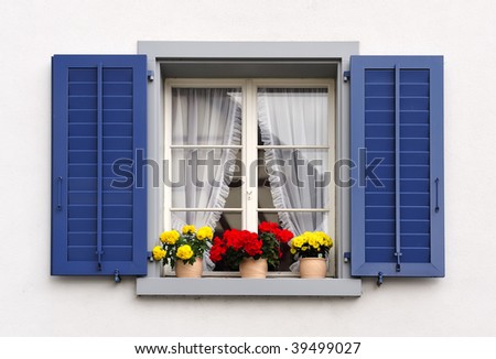  a typical switzerland window with louvered shuters and square paned windows with flowers in hanging flower pots