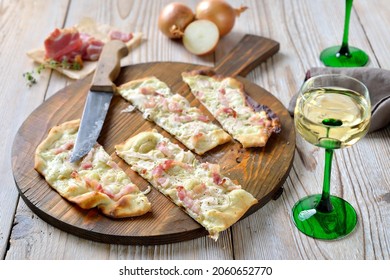 Typical tarte flambée from Alsace with sour cream, onions and smoked bacon hot from the oven, served with Alsatian white wine - Powered by Shutterstock