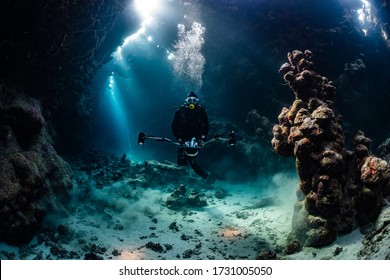 typical underwater cave in a red sea reef with an underwater photographer diver