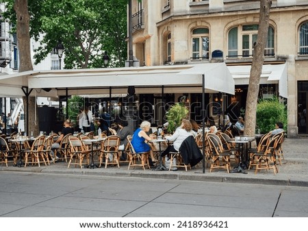 Typical view of the Parisian street with tables of brasserie (cafe) in Paris, France. Cozy cityscape of Paris. Architecture and landmarks of Paris.