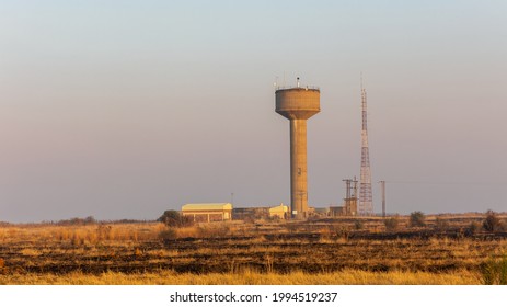 Typical Winter Scene In Rural South Africa With Burnt Grass Land And A Water Reservoir And Communication Tower And Hazy Air Pollution  