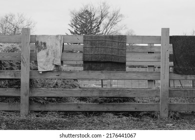 Typical Wooden Fence Down On The Farm With Dirty Towels And Laundry Air Drying From The Railing In Black And White.