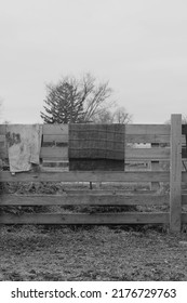 Typical Wooden Fence Down On The Farm With Dirty Towels And Laundry Air Drying From The Railing In Black And White.