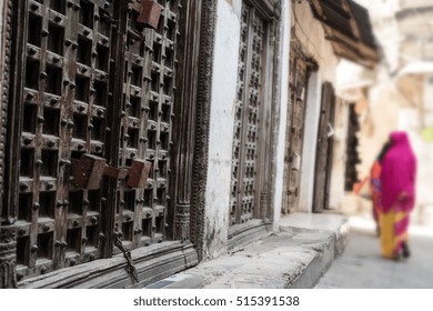 Typical Zanzibar Town Street With Old Iron Doors And Wooman Walking Away, Africa