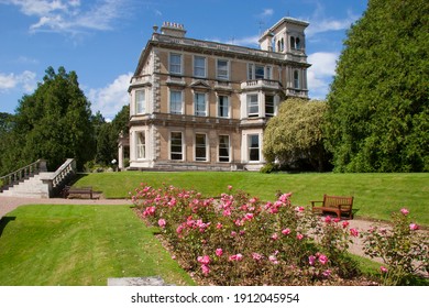 Typically English University Landscape Garden With Hedges, Fences, Plant And Flower Beds, Lawn And Garden Furniture