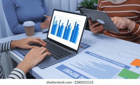 Typing laptop and using tablet, small business accounting team meeting three asian people with salary monthly charts data, basic business accounting and bookkeeping concept.