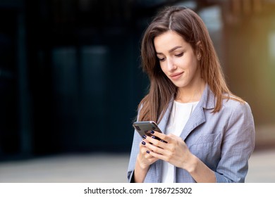 typing a message, a female,  European woman sending an SMS message, sends SMS to his mobile smartphone. Serious young businessman businessman in glasses, businesswoman looks at his mobile phone