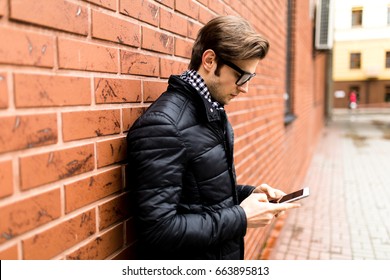Typing text message side view of handsome young man in smart casual wear holding mobile phone