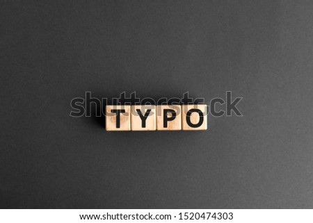 Typo - word from wooden blocks with letters, a typographical error typo concept, random letters around, top view gray background