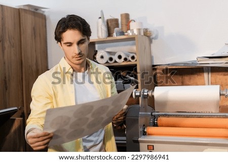 typographer looking at printed paper near professional print plotter