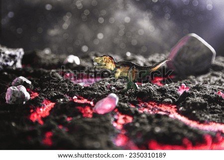 Tyrannosaurus on a stone escapes from burning lava. Creative burning scenery with a small miniature. End of the dinosaur age.