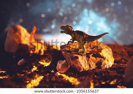 Tyrannosaurus on a stone escapes from burning lava. Creative burning scenery with a small miniature. End of the dinosaur age.