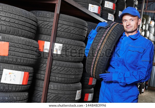 Tyre replacement. mechanic holding tire in\
store warehouse