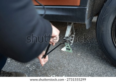 Tyre replacement process with car lifted on a jack.