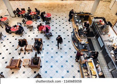 Tysons Corner, USA - January 26, 2018: High Angle View On Food Court, Starbuck's Cafe, People Sitting On Chairs By Tables, Drinking Coffee, Eating In Shopping Mall In Virginia