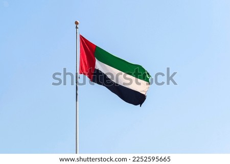 UAE flag waving in the blue bright sky, national symbol of UAE