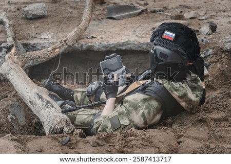 UAV operator with a remote control sitting in a trench. The concept of unmanned technologies in modern warfare. bombing reconnaissance drone. A soldier controls a drone. the remote control is in hands