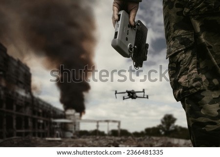 UAV operator with a remote control stands against the background of a destroyed building with black smoke in city. The concept of unmanned technologies in modern warfare. bombing reconnaissance drone