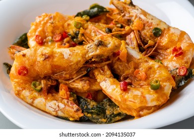 udang saus telur asin or Salted egg fried shrimp with curry leaves served on white plate and isolated on gray background.