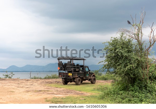 UDAWALAWE, SRI LANKA - 12 NOVEMBER, 2019: Off\
road car for safari on the shore of a lake at sunset in the\
Udawalawe National Park on the island of Sri\
Lanka