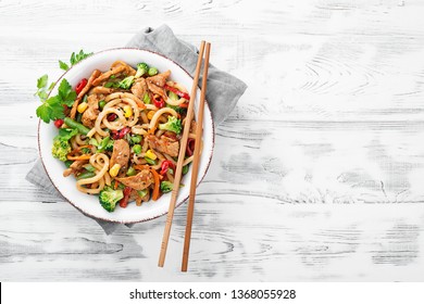 Udon Stir Fry Noodles With Pork Meat And Vegetables In A White Plate On White Wooden Background.