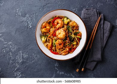 Udon stir-fry noodles with shrimp in bowl and chopsticks on dark stone background copy space - Powered by Shutterstock