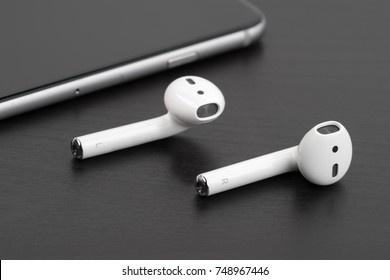 UFA, RUSSIA - OCTOBER 20, 2017: AirPods wireless headphones developed by Apple Inc. AirPods is on the open box and iphone.