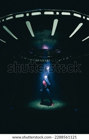 A UFO alien ship steals a man at night on the street at night in the fog. Vertical.
