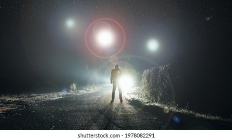 UFO concept. Glowing orbs, floating above a misty road at night. With a silhouetted figure looking at the lights.               