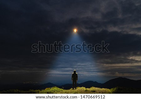 The UFO shines on a male standing on the mountain