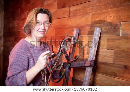 Ugly adult aged woman on the couch with hay in the room or in stable. Rustic style in the interior during photoshoot