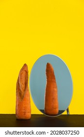 Ugly carrot in front of mirror, reflection, reverse side. Concept - reduction of organic food waste. Crooked vegetables and fruits can be eaten.